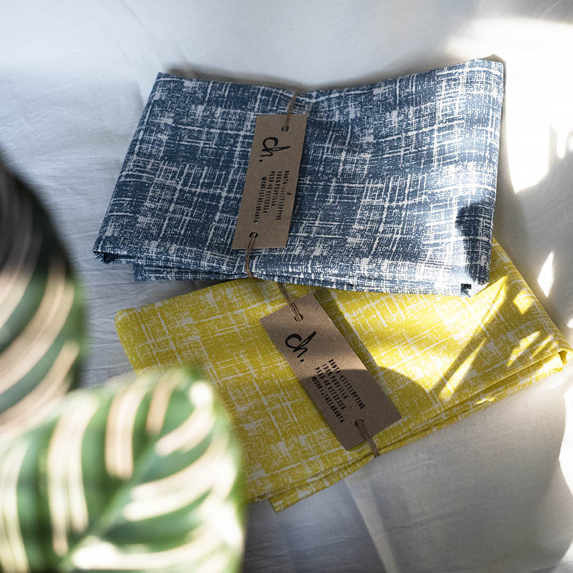 Routa-keittiöpyyhkeet, värivaihtoehdot sininen ja keltainen, taiteltuina limittäin, päällekkäin, valkoista taustaa vasten.