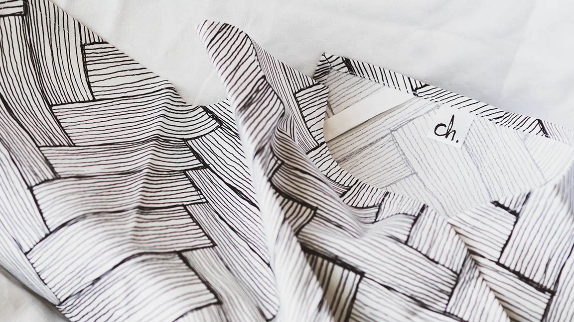 Mustavalkoinen keittiöpyyhe Ruotia-kuosilla levitettynä valkoista taustaa vasten