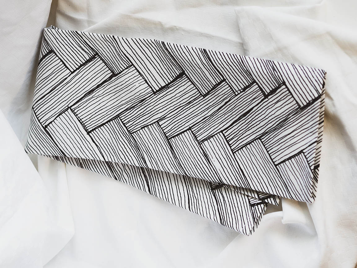 Mustavalkoinen keittiöpyyhe Ruotia-kuosilla valkoista taustaa vasten