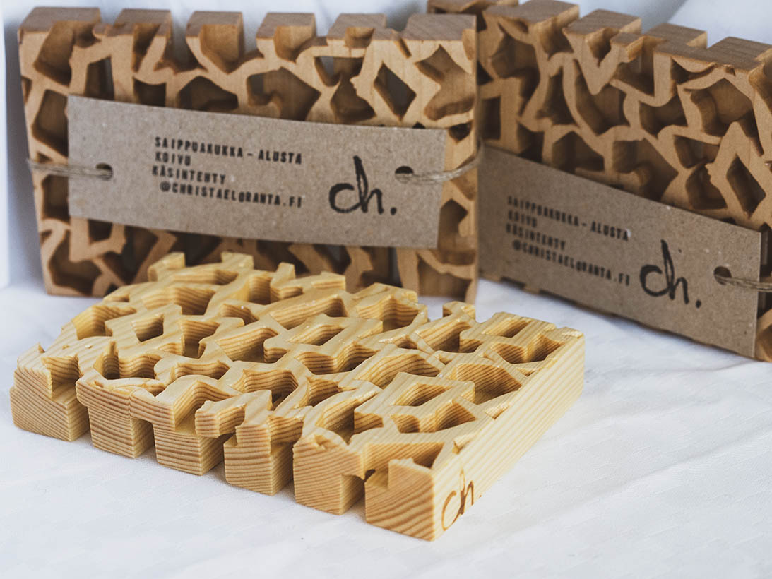 Useampi Saippuakukka-alusta valkoista taustaa vasten. Kuvassa alustoja sekä koivusta että männystä