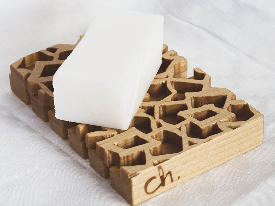 Koivusta jyrsitty puinen saippua-alusta valkoista taustaa vasten. Päällä pala valkoista saippuaa.